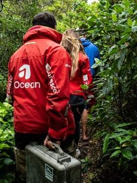 Membre de l’équipe en veste rouge progressant dans la végétation